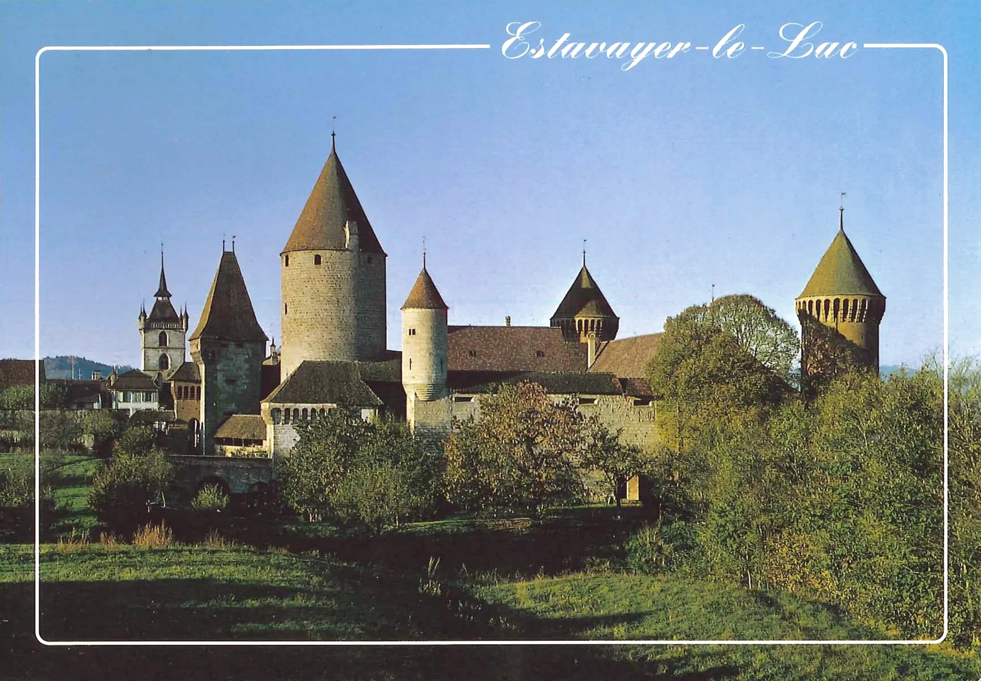 Carte postale en couleur : le château et le clocher de la collégiale au-dessus du pré, en fin d’après-midi